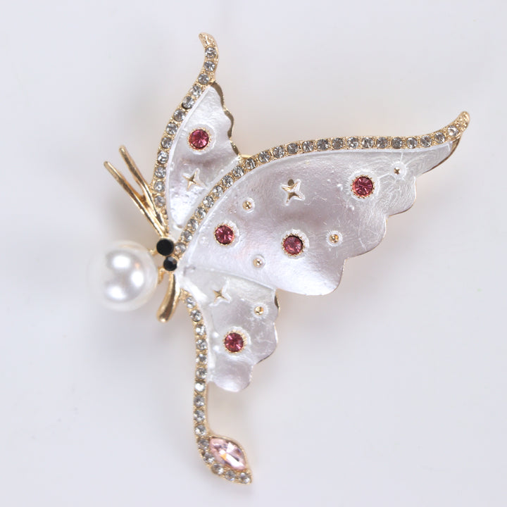 Pearlescent white enamel butterfly brooch pin with a large pearl accent and pink crystals against a white background by Delemon