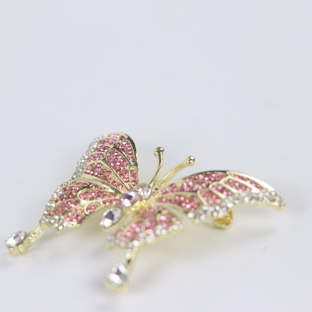 Sparkling gold butterfly brooch pin embellished with pink and clear crystals on a white background by Delemon