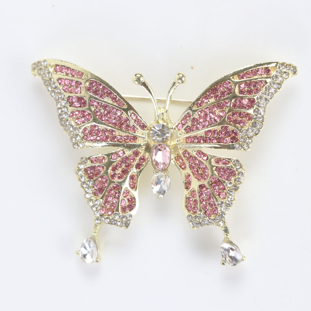 Sparkling gold butterfly brooch pin embellished with pink and clear crystals on a white background by Delemon