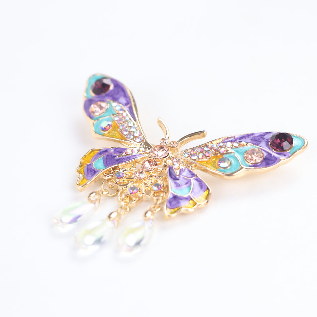 Colorful purple and turquoise enamel butterfly brooch pin with sparkling crystals and three dangling teardrop beads on a white background by Delemon