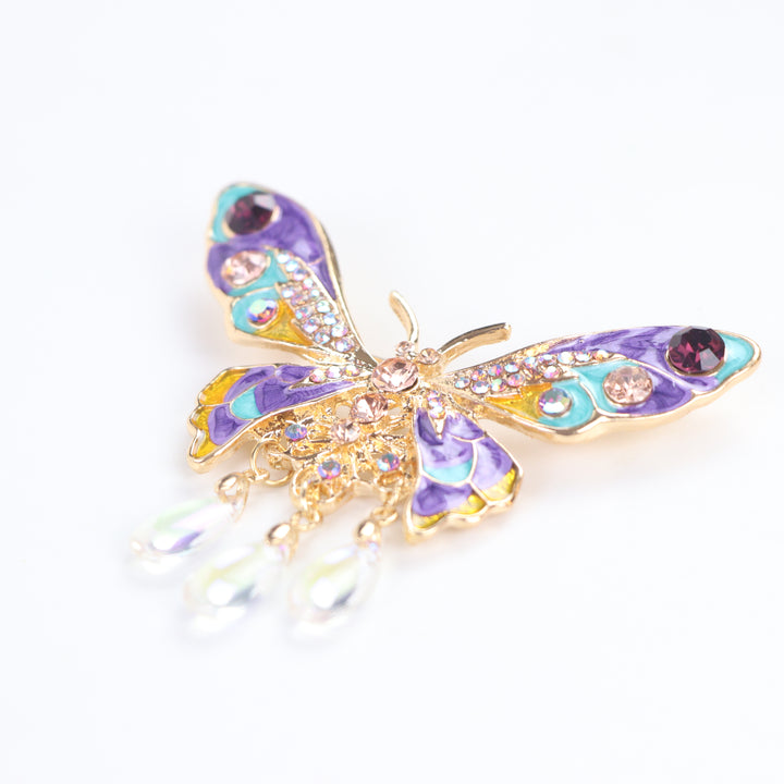 Colorful purple and turquoise enamel butterfly brooch pin with sparkling crystals and three dangling teardrop beads on a white background by Delemon
