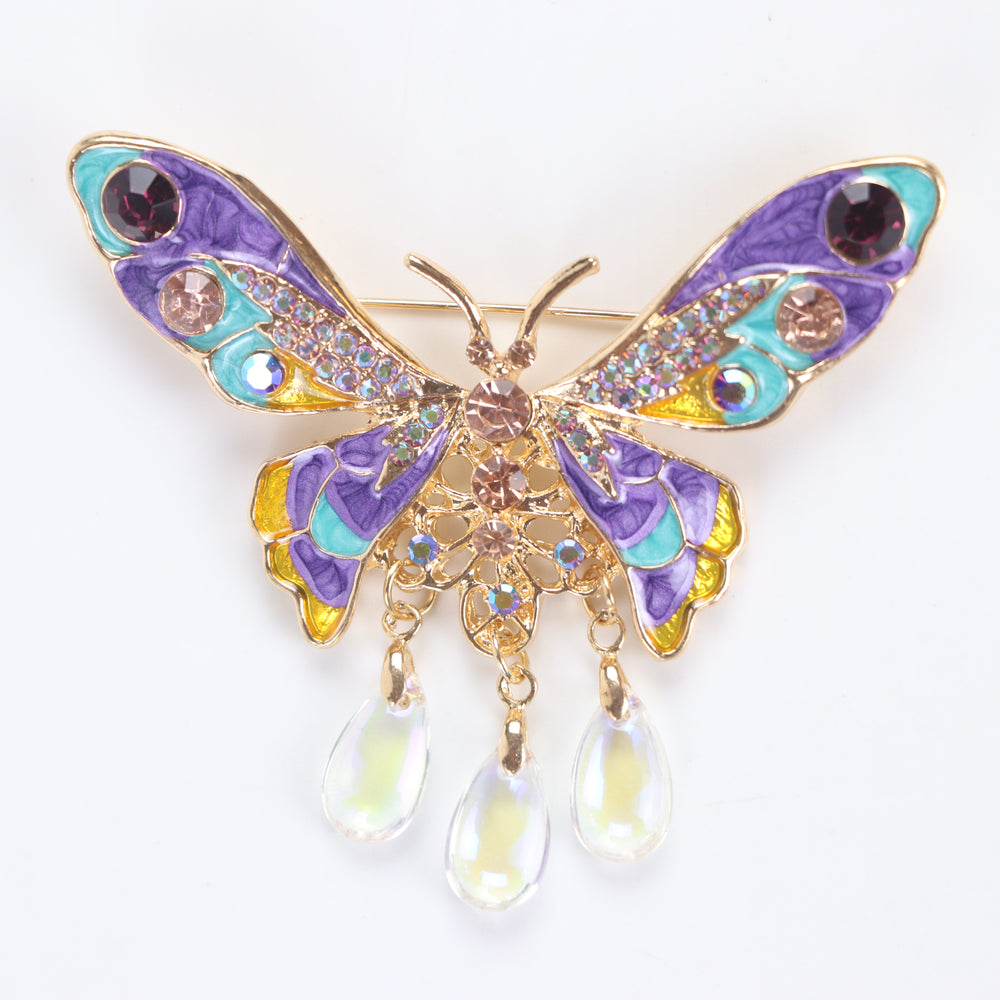 Colorful purple and turquoise enamel butterfly brooch pin with sparkling crystals and three dangling teardrop beads on a white background by Delemon