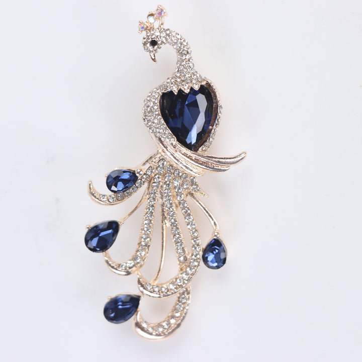 Majestic peacock brooch pin with clear pavé crystals and deep blue teardrop gems on a white background by Delemon