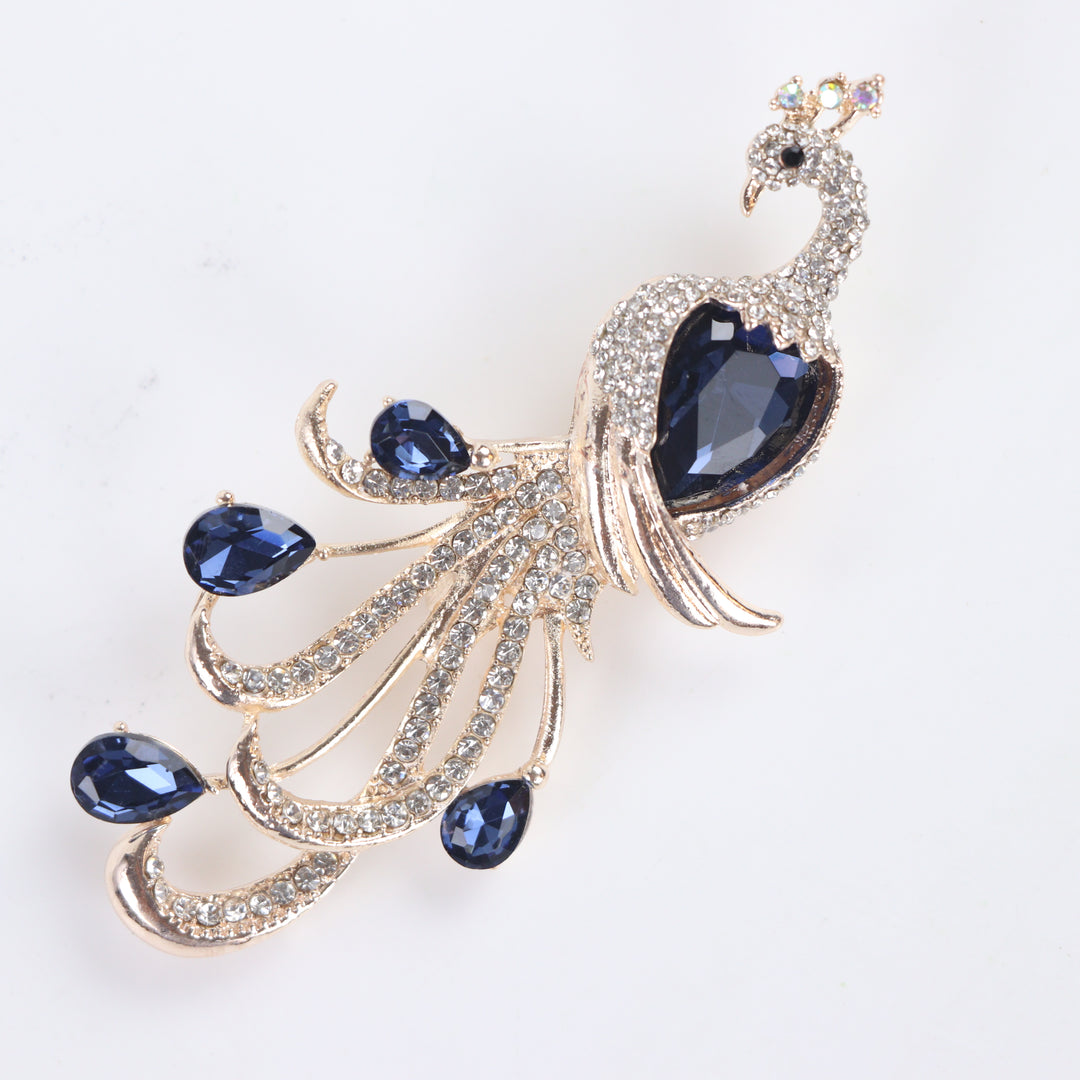 Majestic peacock brooch pin with clear pavé crystals and deep blue teardrop gems on a white background by Delemon