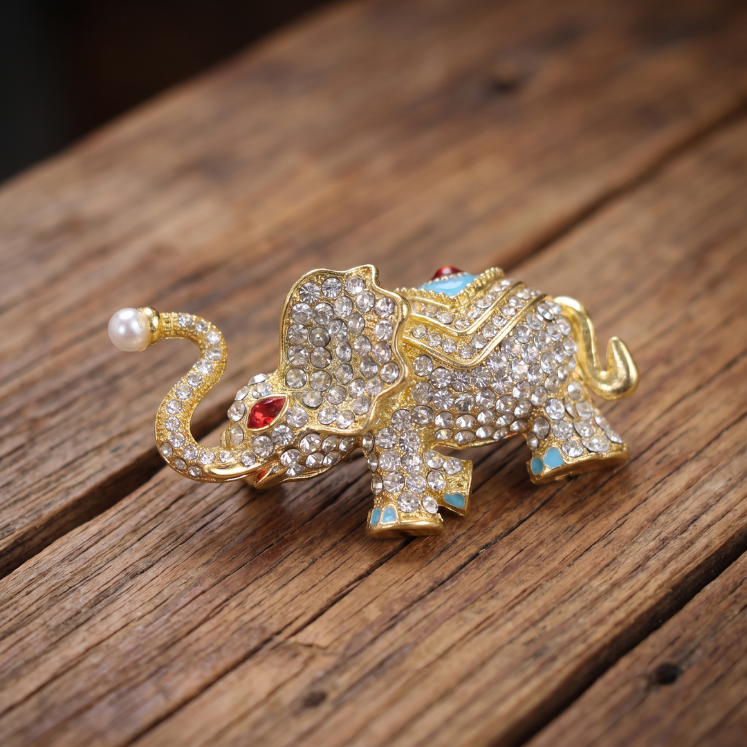 Sparkling gold elephant brooch pin with paved crystals, turquoise enamel saddle, and a pearl trunk tip