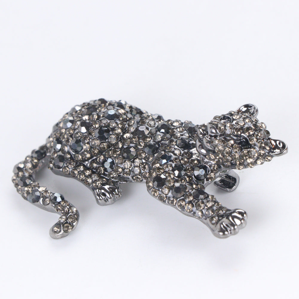 Gunmetal-tone crouching panther brooch pin fully pavé-set with dark hematite and smoky crystals on a white background by Delemon