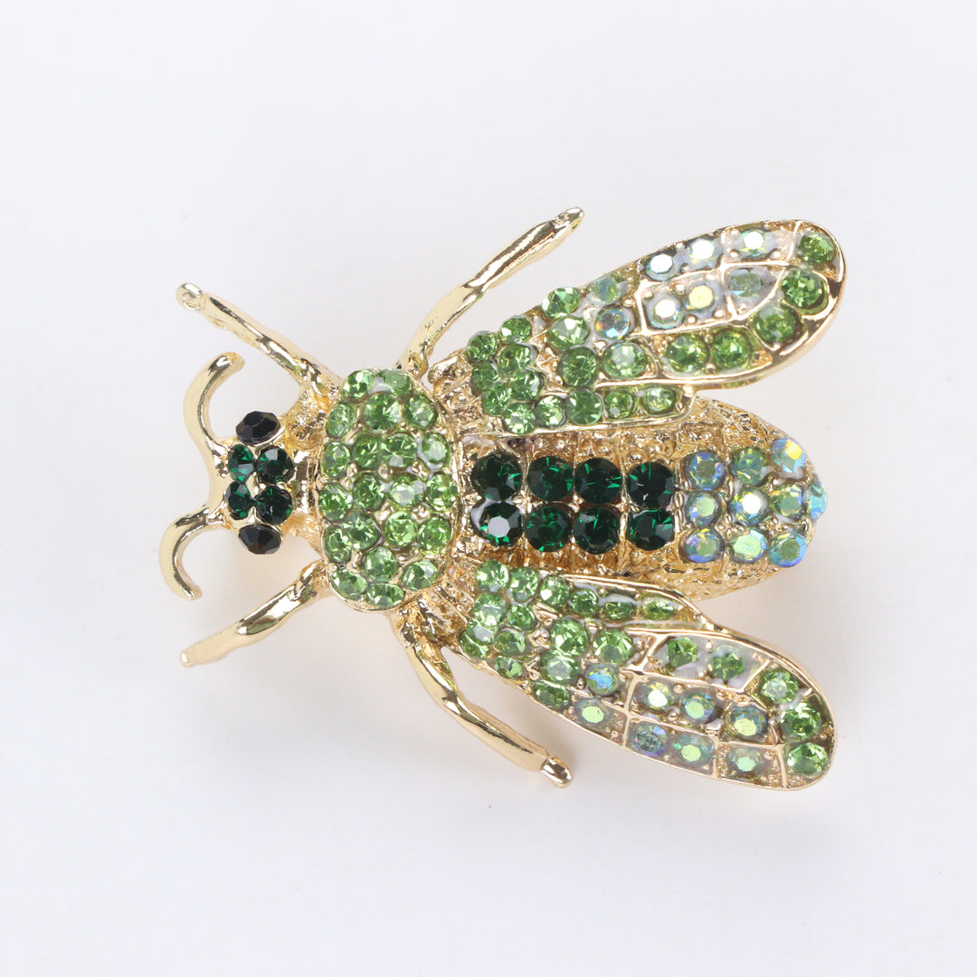 Gold-tone honeybee brooch pin encrusted with peridot and emerald green crystals on a white background by Delemon