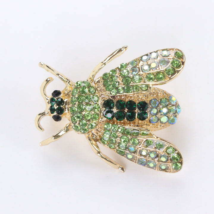 Gold-tone honeybee brooch pin encrusted with peridot and emerald green crystals on a white background by Delemon
