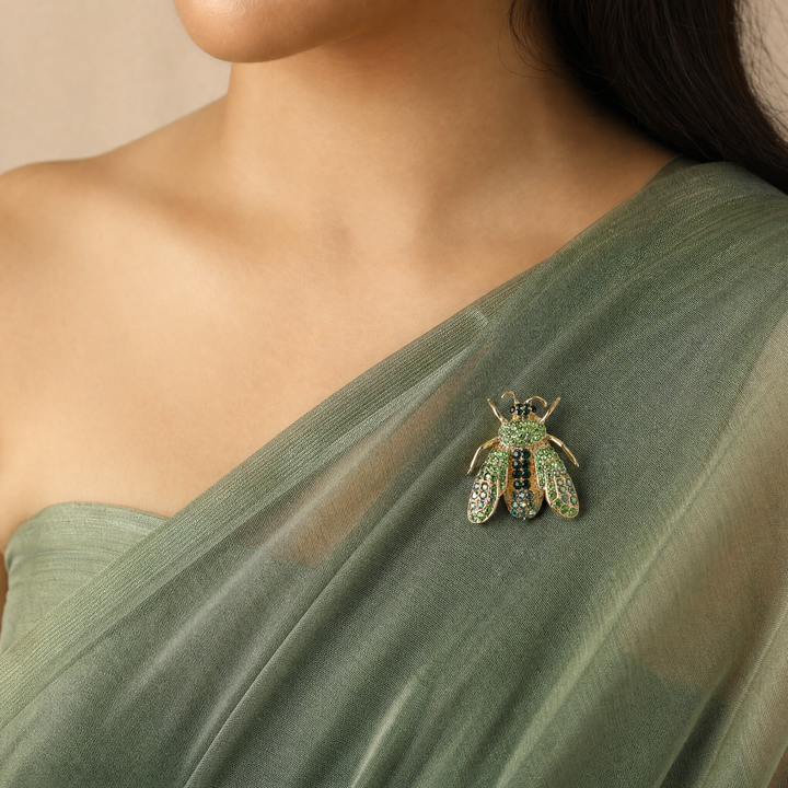 Gold-tone honeybee brooch pin encrusted with peridot and emerald green crystals on a white background by Delemon