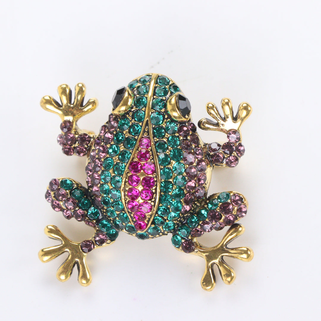 Antique gold-tone tree frog brooch pin encrusted with emerald green, purple, and hot pink crystals on a white background by Delemon