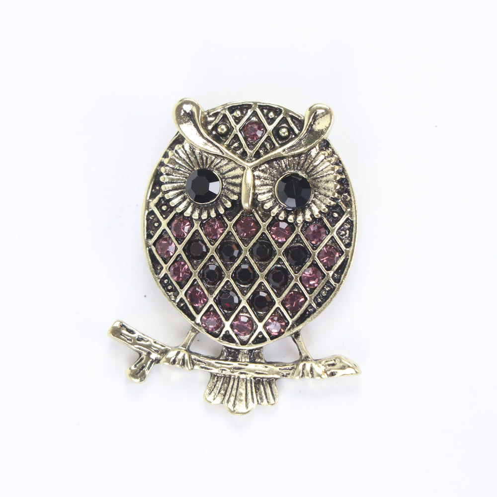 Vintage antique gold owl brooch pin with purple crystal lattice body and black crystal eyes on a branch against a white background by Delemon