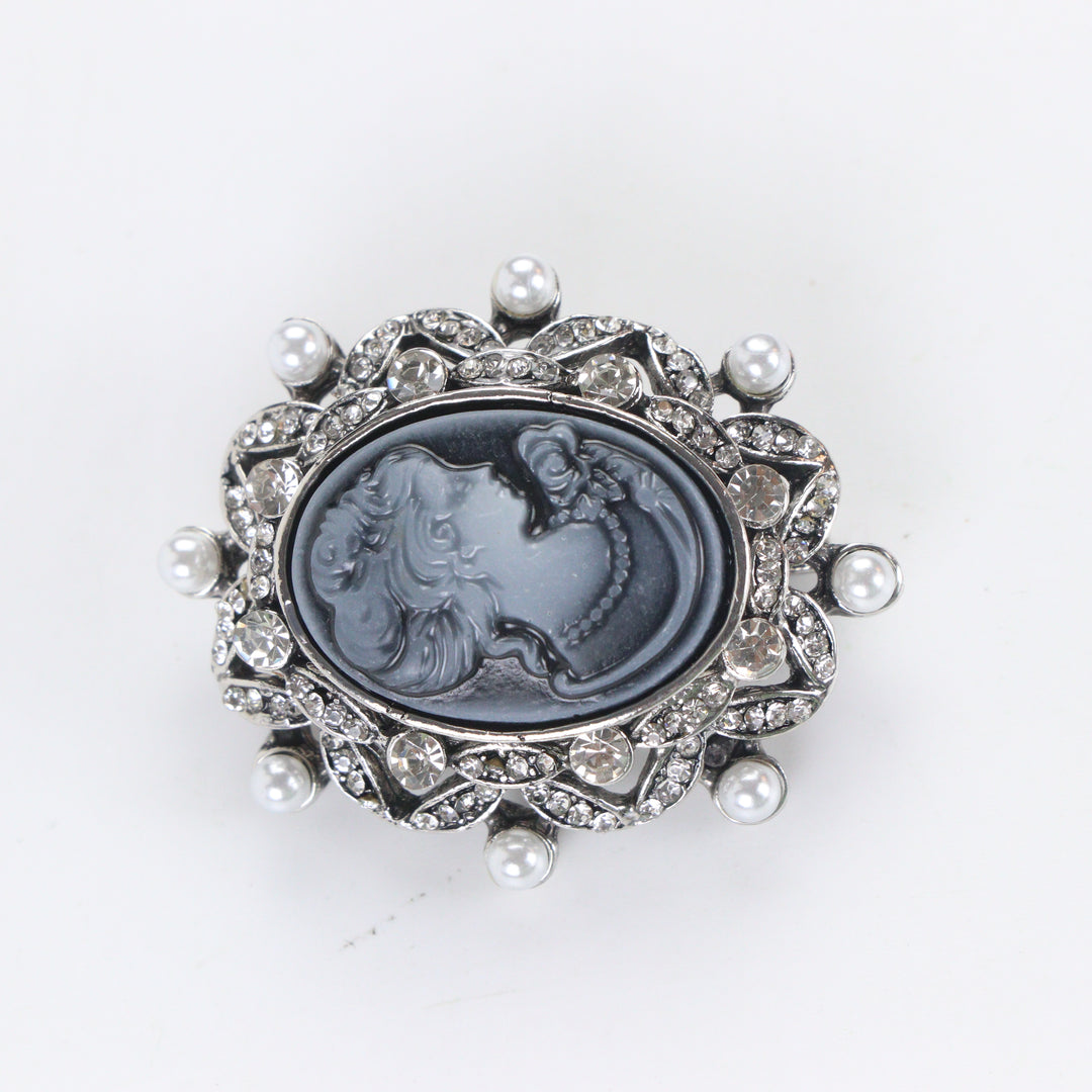 Antique silver-tone oval cameo brooch pin featuring a carved lady profile, clear rhinestones, and pearl trim on a white background by Delemon