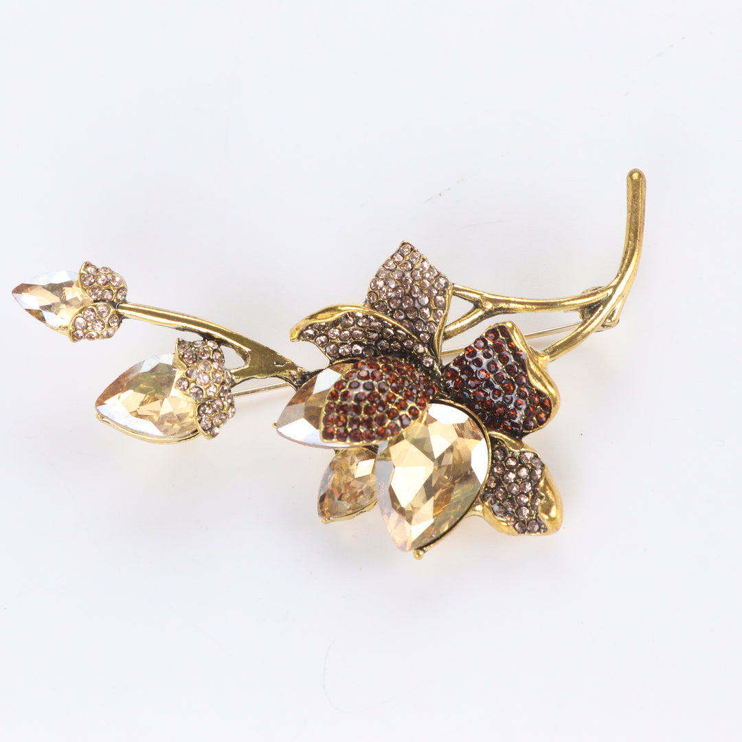 Antiqued gold-tone floral branch brooch pin featuring champagne crystals, topaz rhinestones, and crystal buds on a white background by Delemon