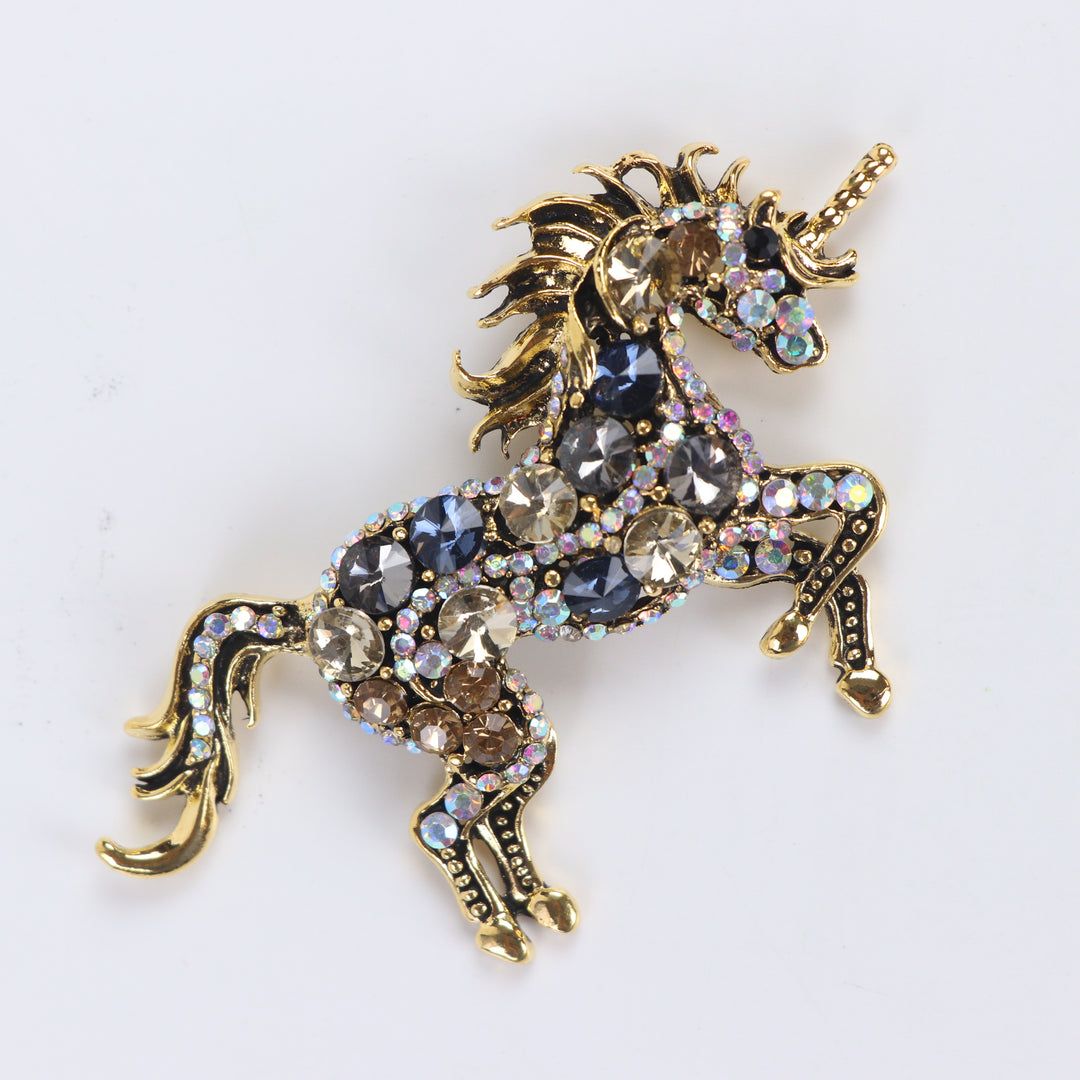 Antique gold unicorn brooch pin encrusted with multi-colored crystals against a white background by Delemon