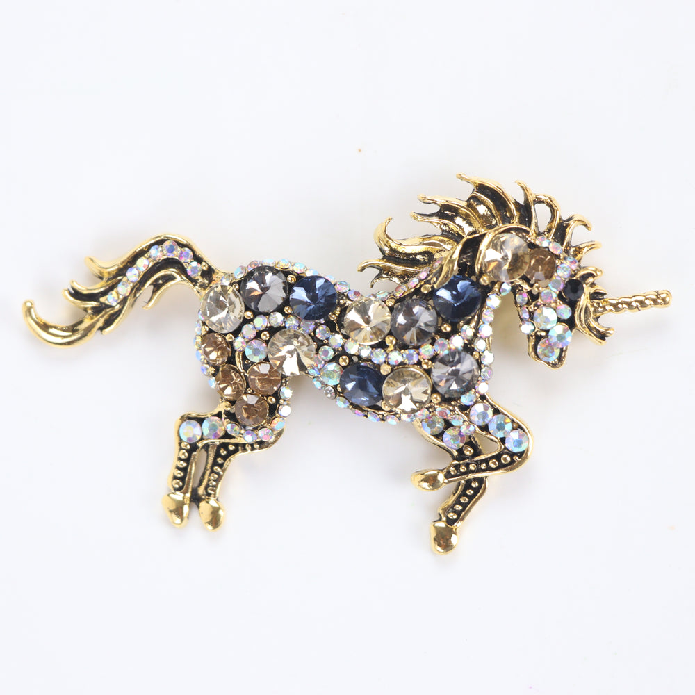 Antique gold unicorn brooch pin encrusted with multi-colored crystals against a white background by Delemon