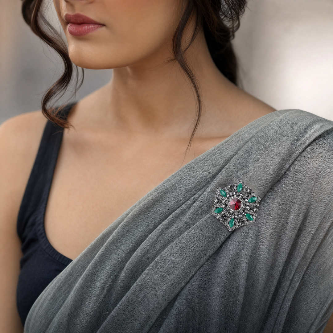 Antique silver-tone filigree starburst medallion brooch pin featuring a ruby red crystal center and jade green marquise accents 